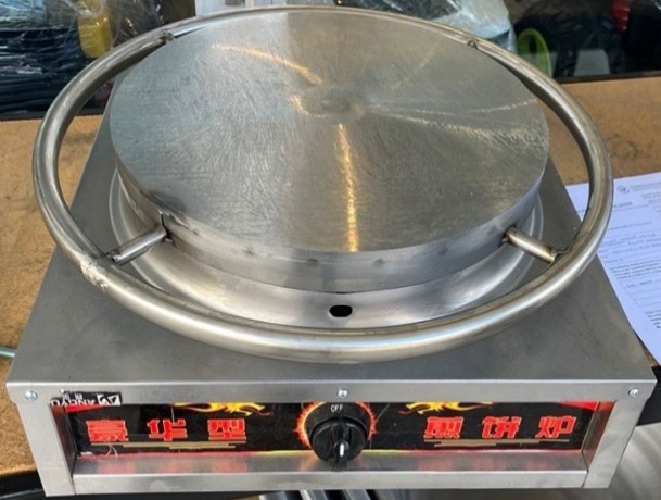 A photo of a silver appliance with a dial and red symbols at the front.