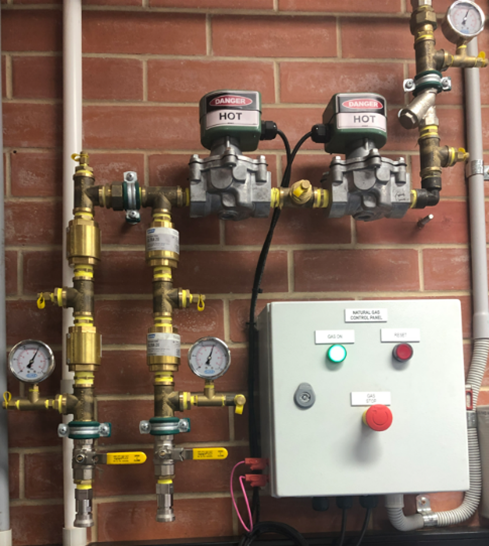 Photo of pipes with gauges and a control panel with buttons.